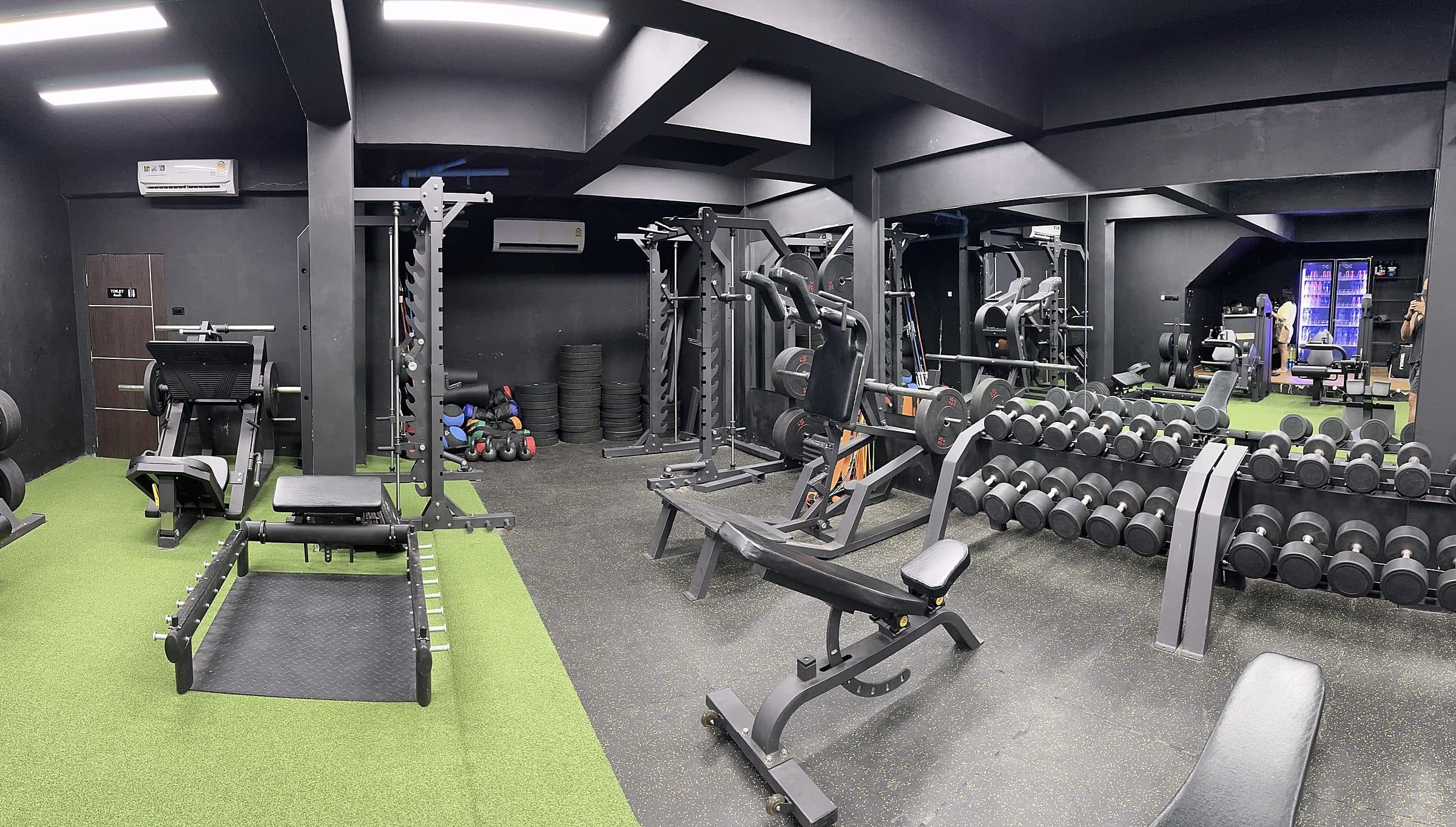 Wide view of the Nordic gym floor with racks, benches and dumbbells