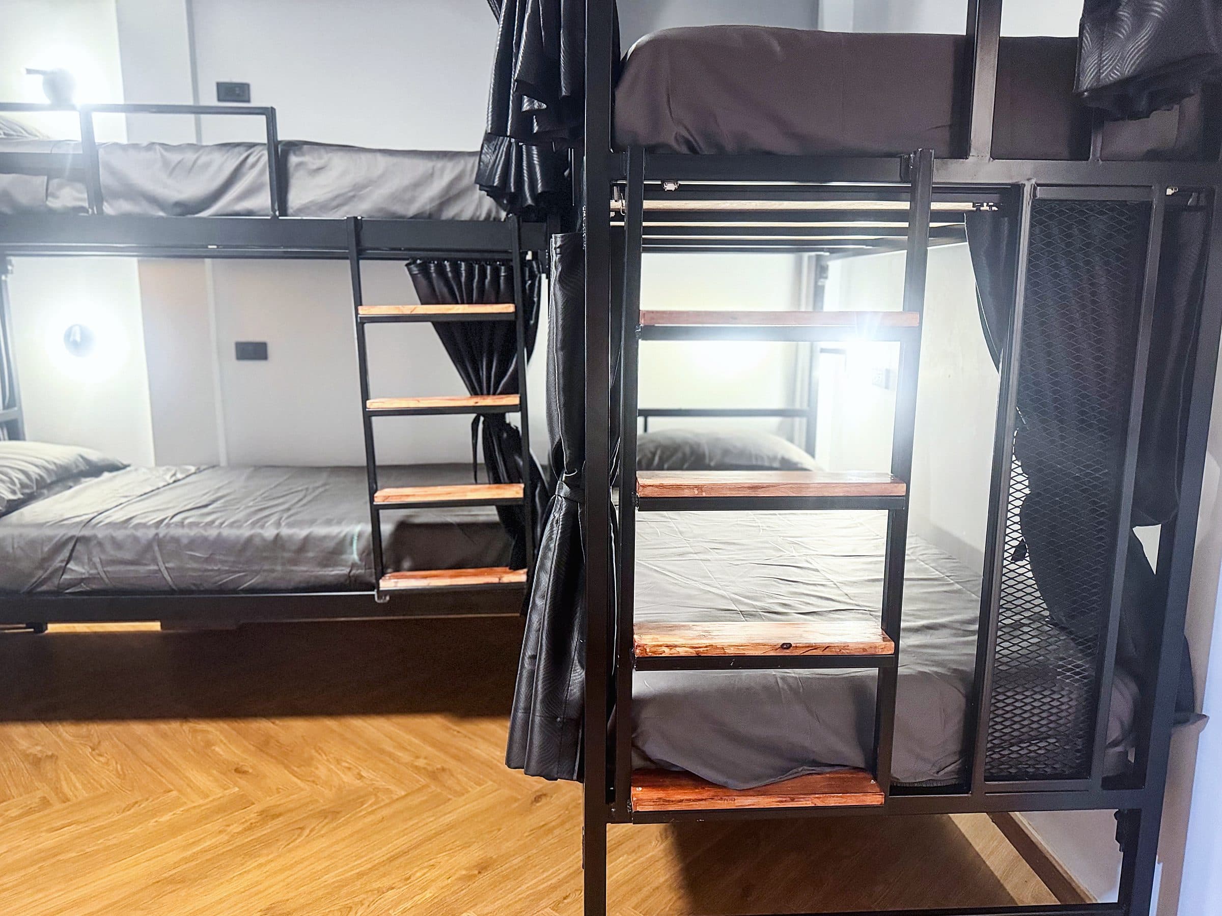 Black metal bunk beds with wooden ladders in the women-only dorm