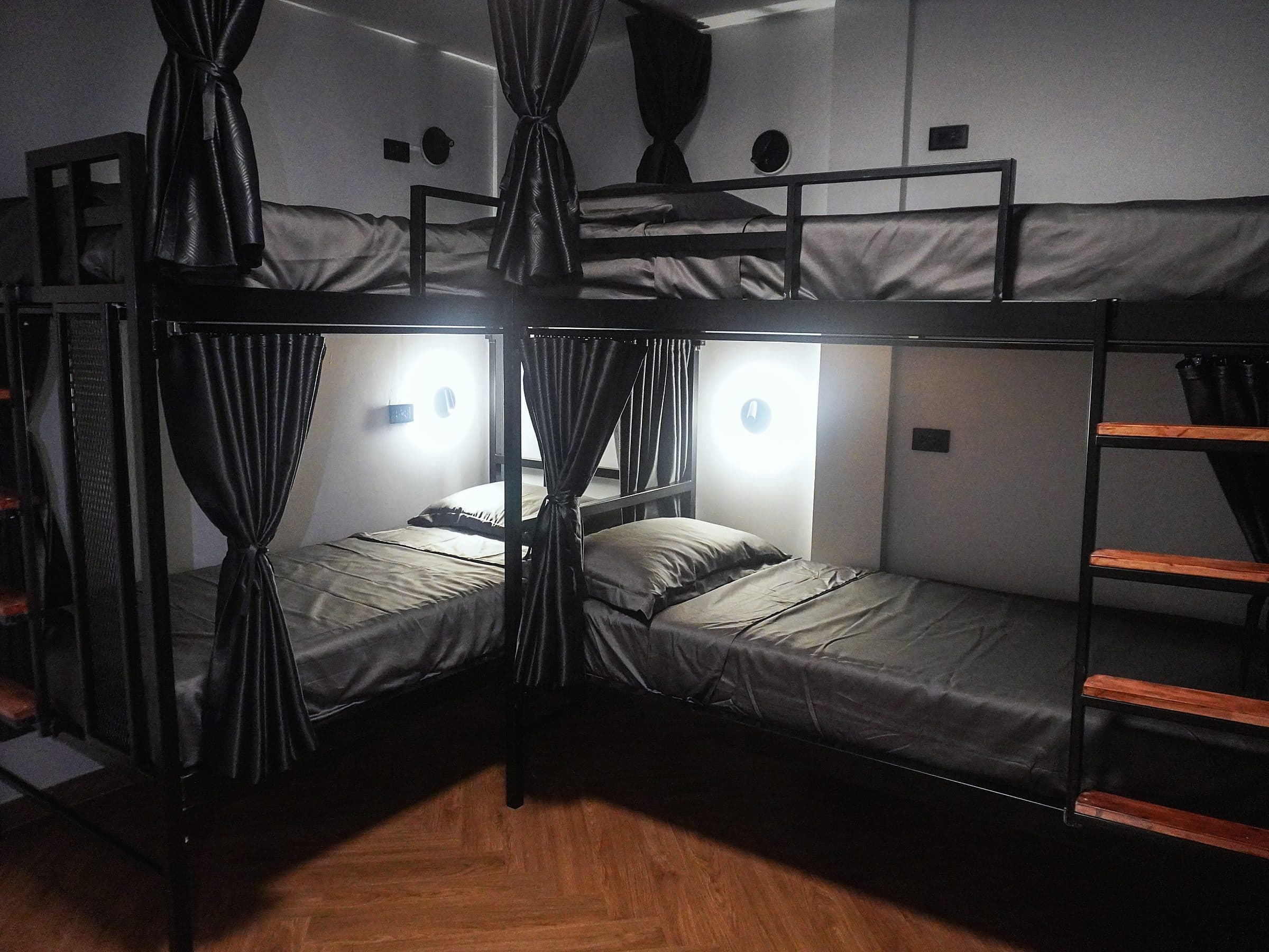 Six-bed dorm with black bunks, privacy curtains and reading lights